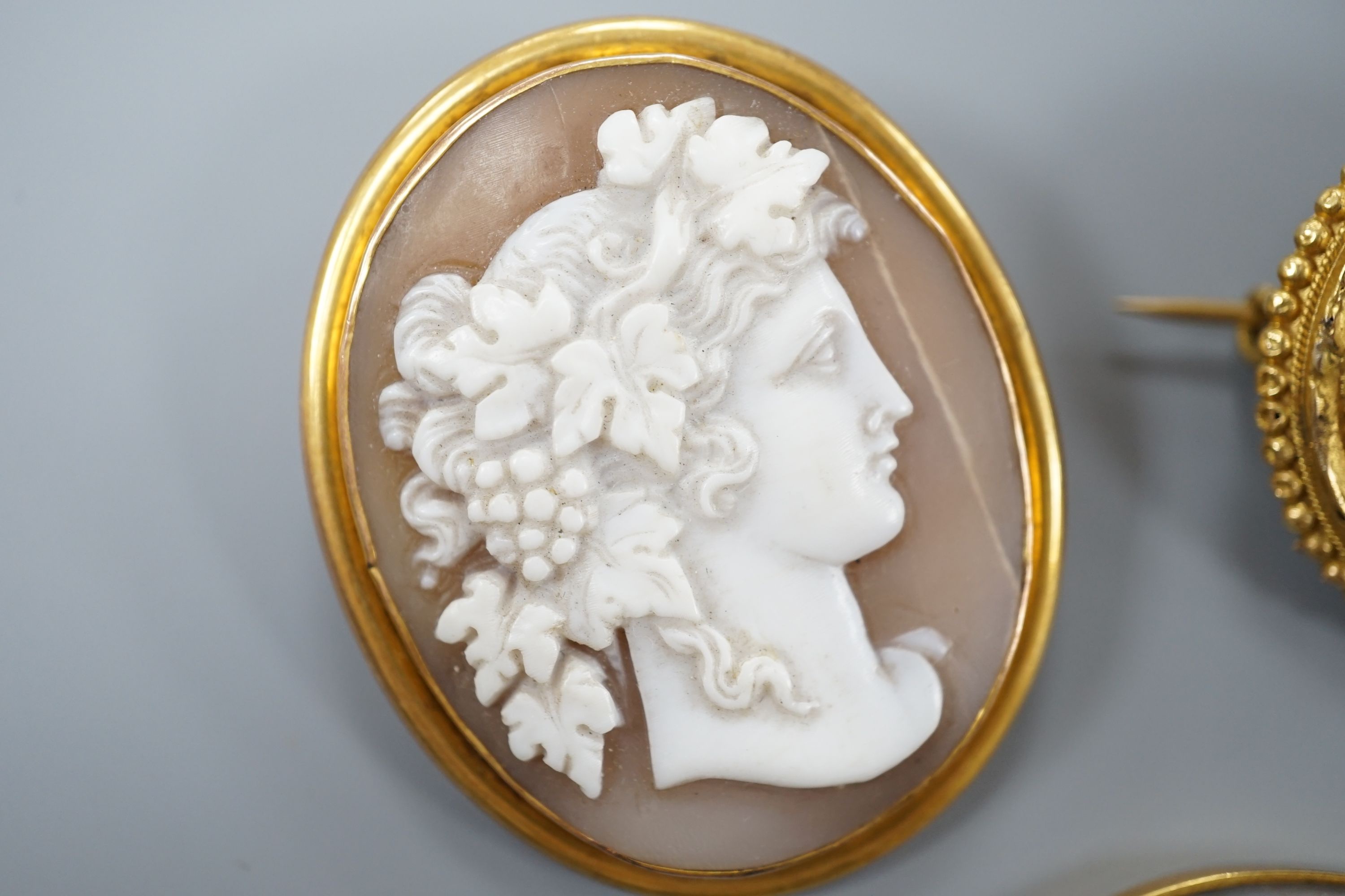 A Victorian yellow metal and cabochon garnet set circular brooch, 31mm, gross 9.3 grams, a stick pin with yellow metal and hardstone cameo set terminal, a mounted Indian miniature, a mounted cameo shell brooch and a Vict